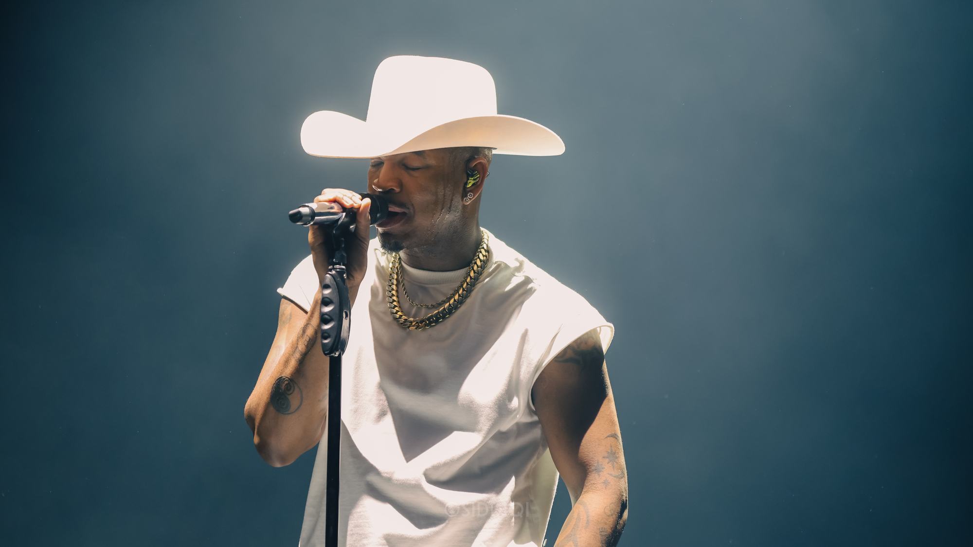 Artist med hat synger i skarpt scenelys