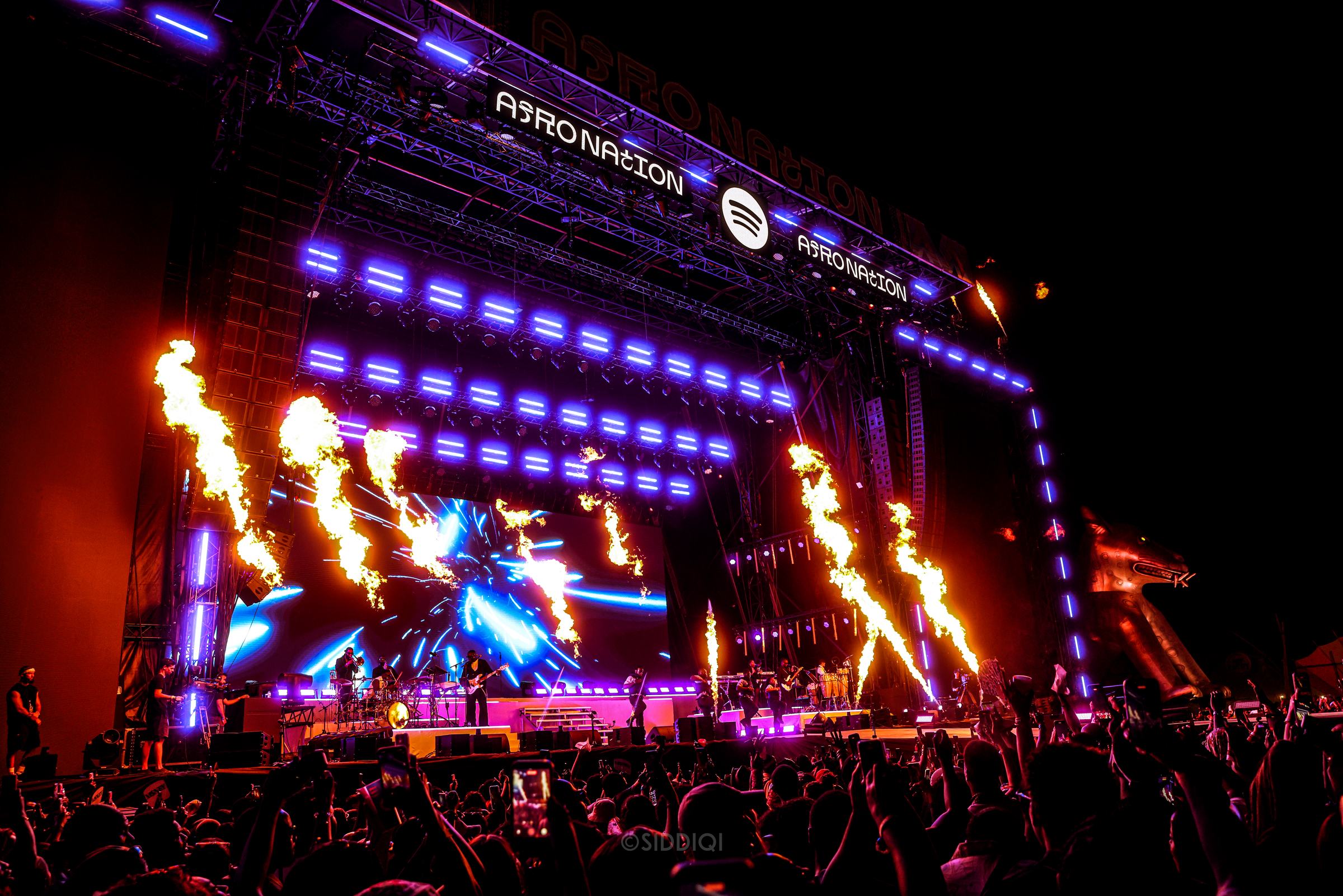 Festivalscene set fra publikum med lysrigge og flammer
