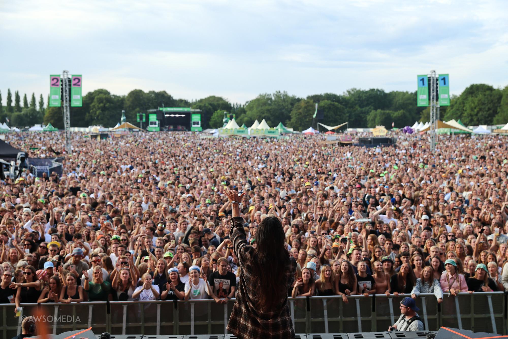 Kunstner peger ud mod stort festivalpublikum fra scenen