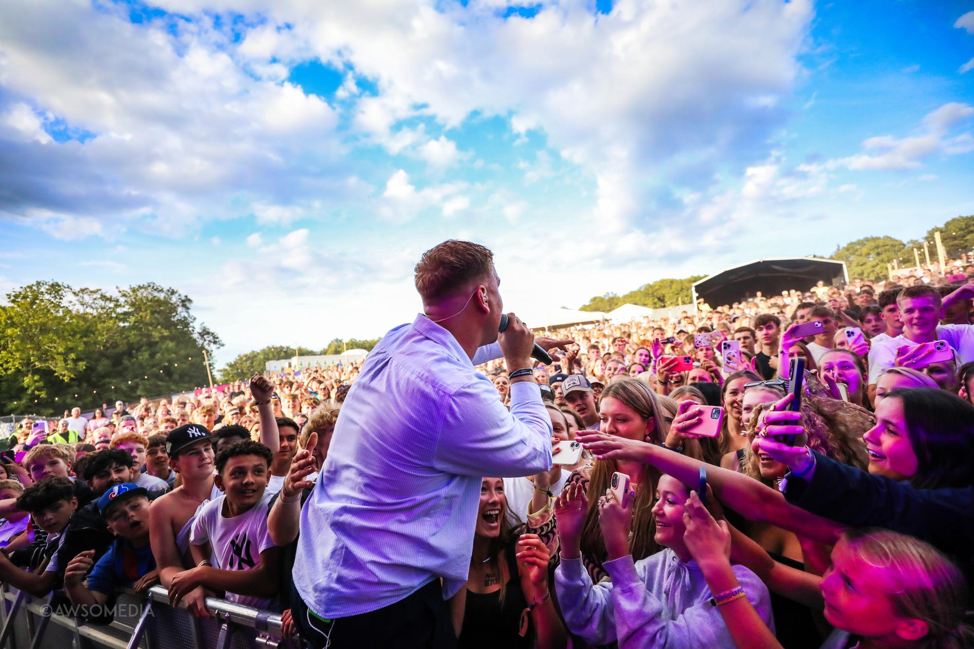 Mand synger til publikum i solrigt festivallys