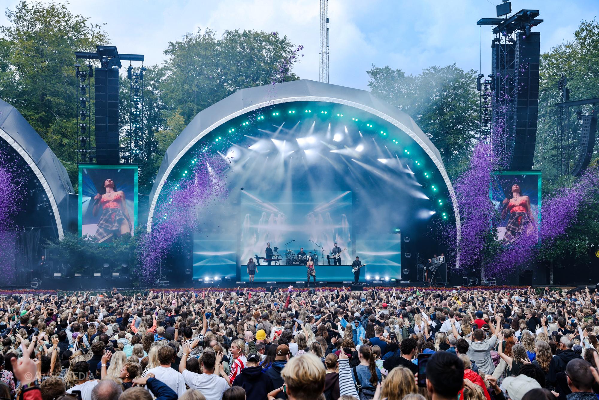 Festivalscene med lilla røg og publikum foran koncert