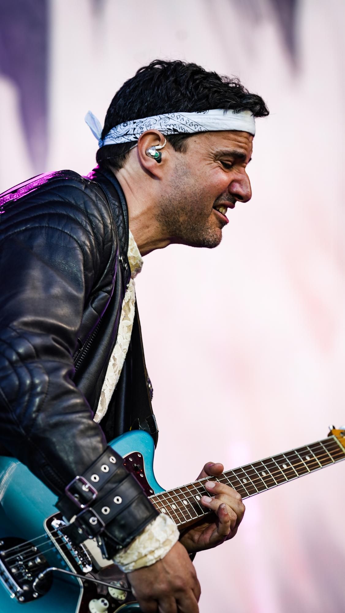 Guitarist med pandebånd spiller intenst på scenen