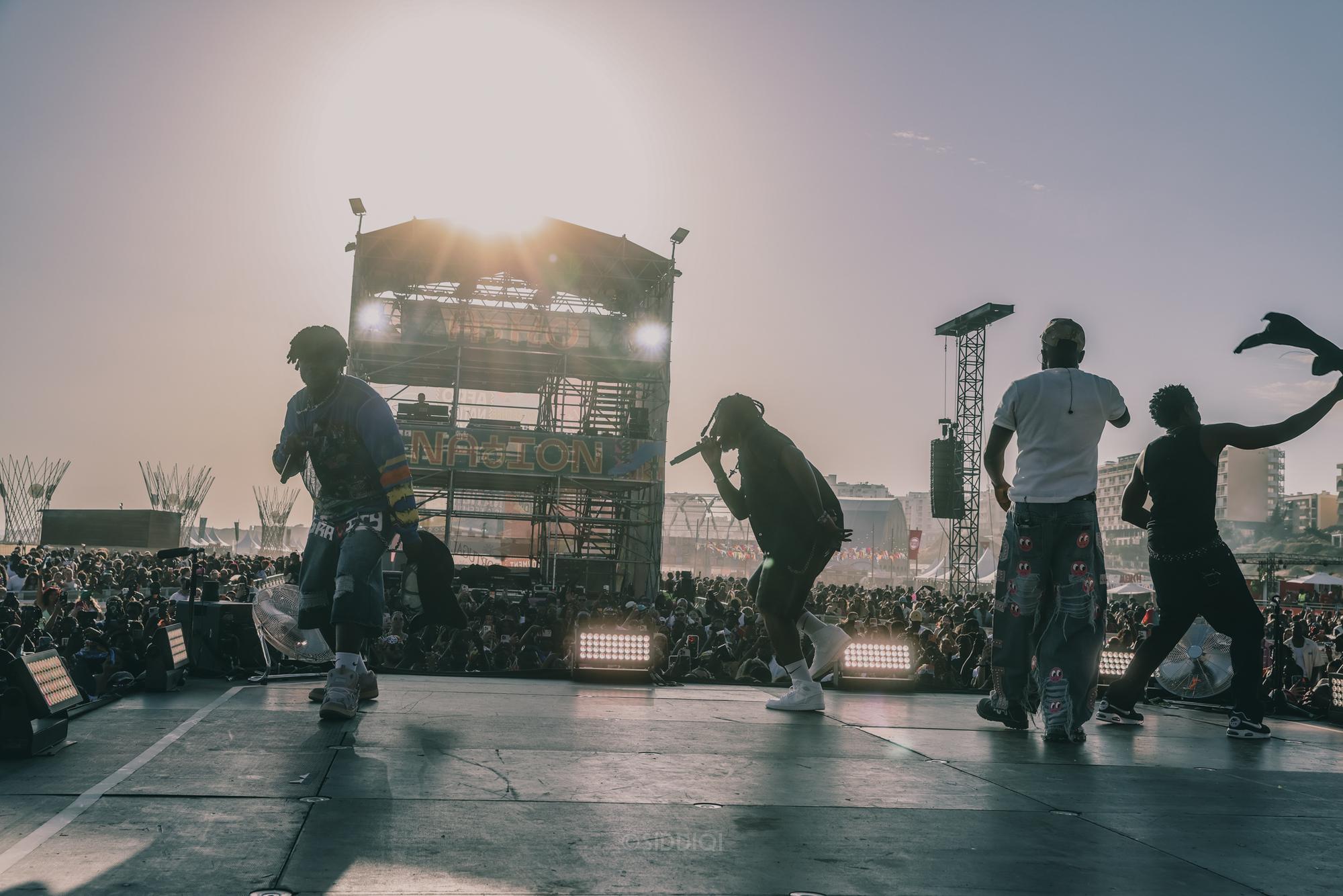 Silhuetter af optrædende danser foran solnedgang på festivalscenen